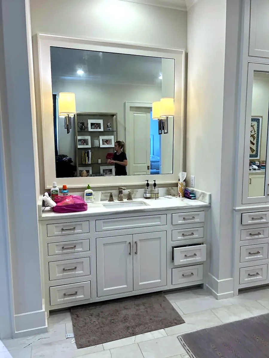 Bathroom with a long double vanity, framed mirror and wall sconces