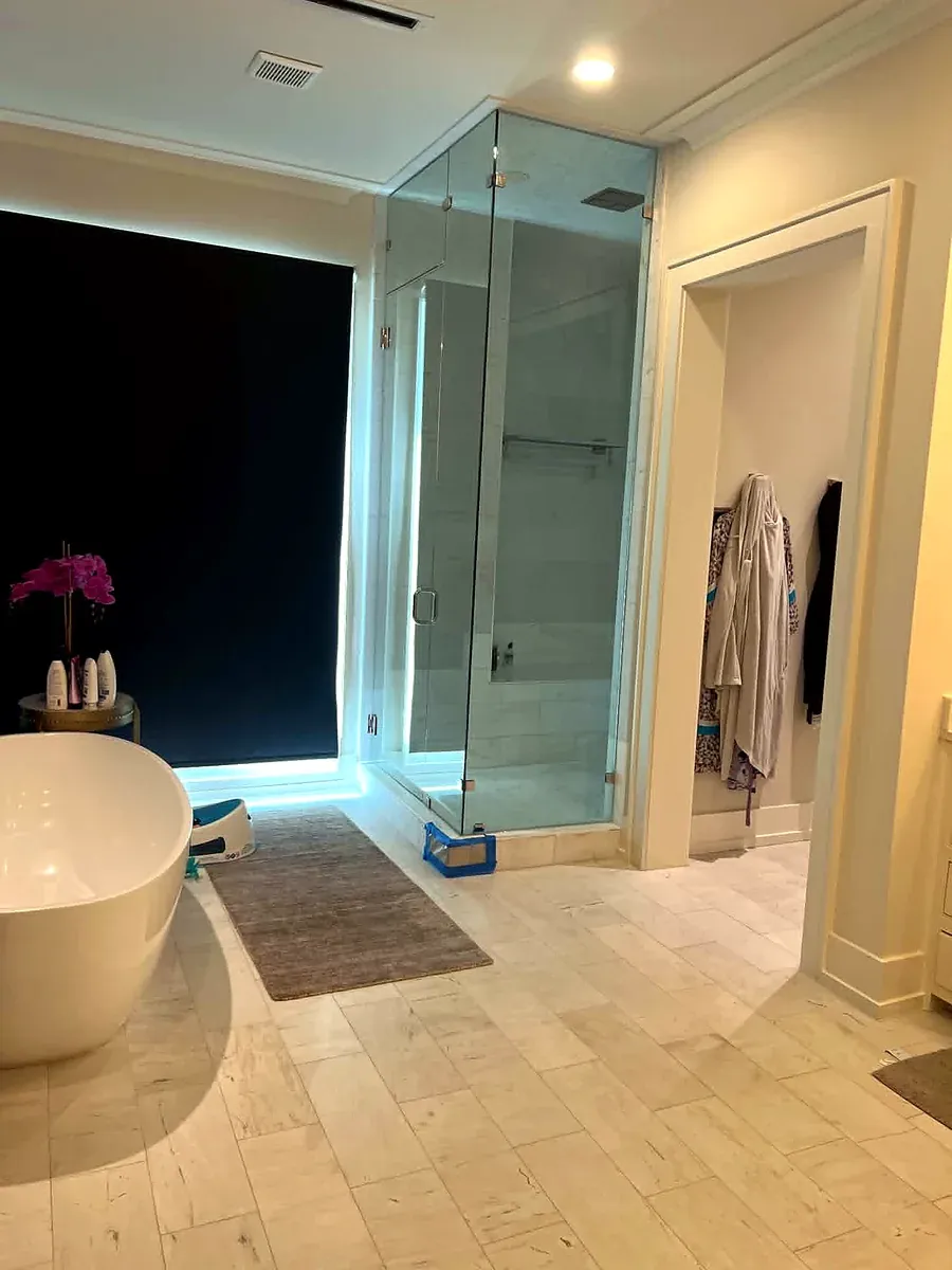 Primary bathroom with a freestanding tub, adjacent frameless glass shower and light wood flooring