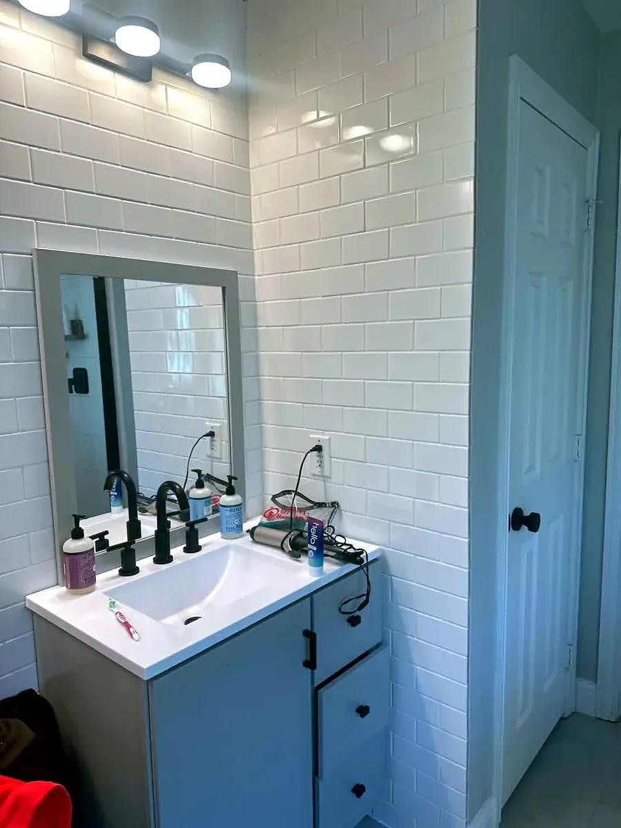 Bathroom remodel with white subway tile, a framed mirror and a modern vanity
