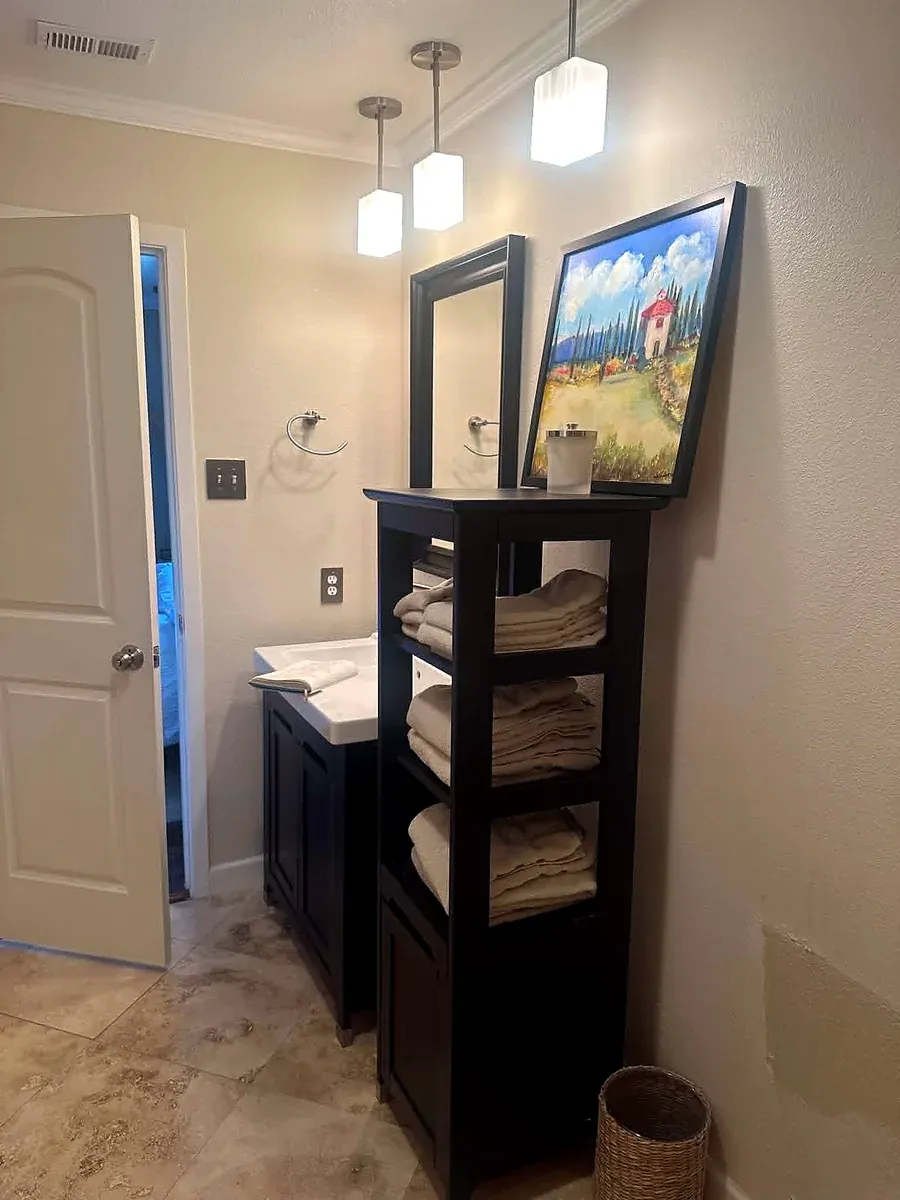 Bathroom vanity with a framed mirror, sconce and open shelving tower