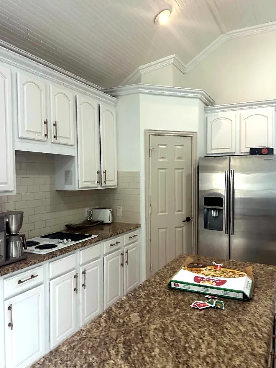 Kitchen with white raised panel cabinets, granite counters and a tile backsplash