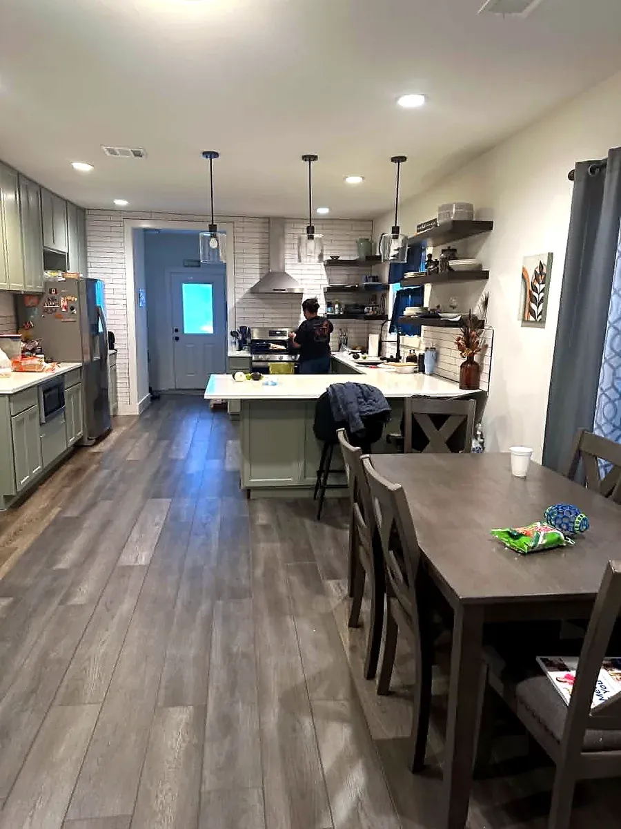 Open kitchen and dining area with a large island, pendant lighting and wood look flooring