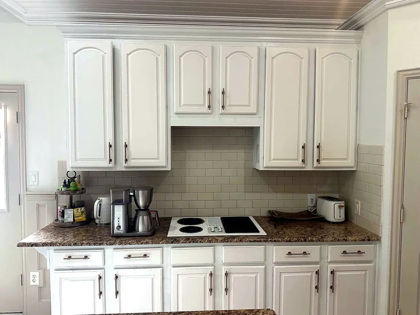Galley kitchen with white cabinetry, granite counters and a tile backsplash