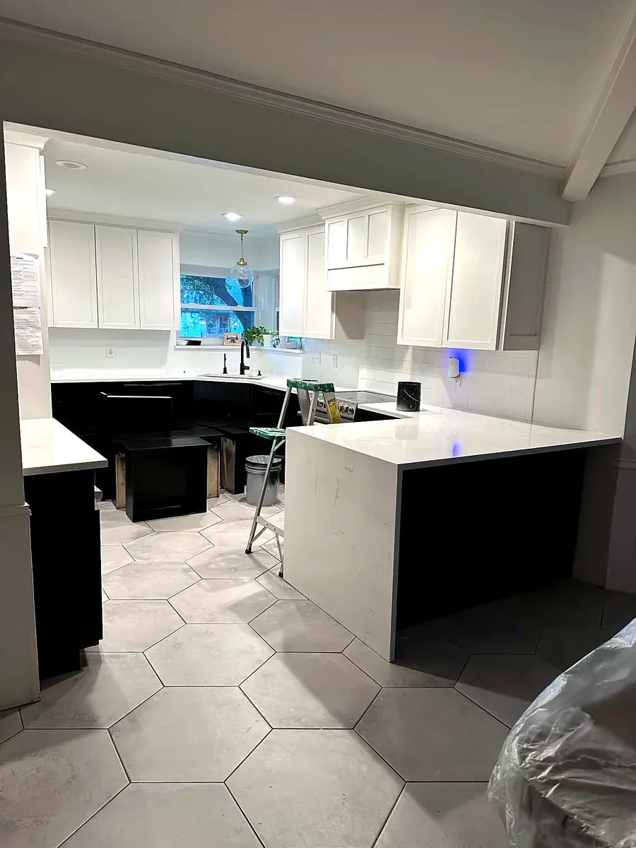 Kitchen remodel with a dark island, hexagon tile floor and white perimeter cabinetry