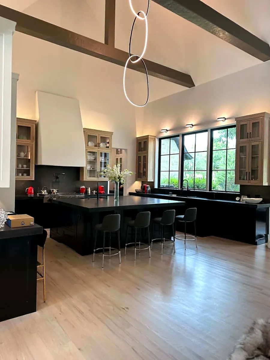 Open plan kitchen remodel by the Teddy team with a black island, exposed beams and white oak floors