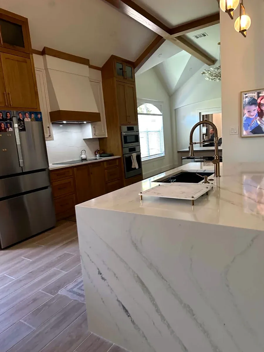 Kitchen remodel with a waterfall edge quartz island, brass faucet and a vaulted beamed ceiling