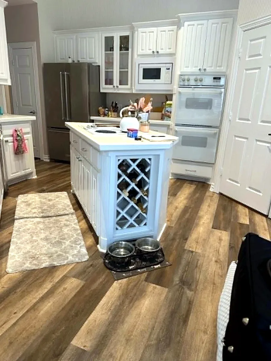 Kitchen with white cabinetry, a painted island and wood look flooring