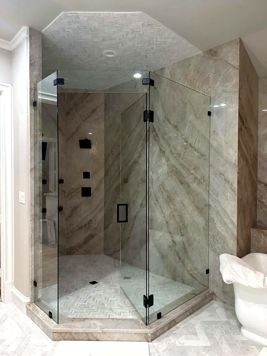 Frameless glass walk in shower with large format marble panels and matte black fixtures